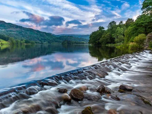 The River Rothay flowing over the weir at Grasmere Lake towards Rydal. A lovely summer morning sky over the Barrowdale fells in the distance 43 jpg
